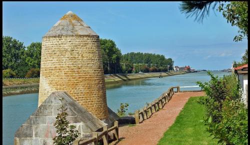 un pilier en briques à côté d'une rivière avec une clôture dans l'établissement Meublé bord de Mer, à Gravelines