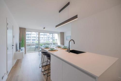 een witte keuken met een wastafel en een aanrecht bij Mosselbank 211 in Nieuwpoort