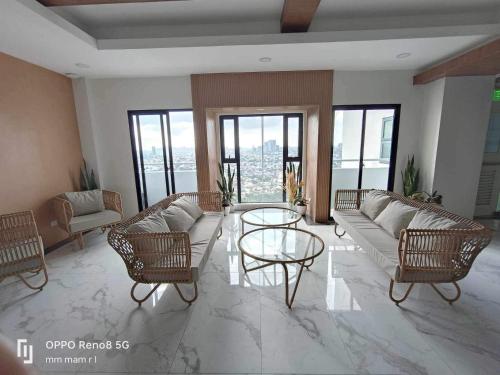 a living room with a couch and chairs and windows at 19F One Katipunan Residence in Manila