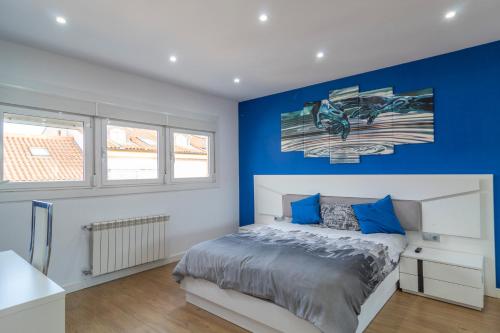 a bedroom with blue walls and a bed with blue pillows at APARTAMENTO HOLIDEA centro ciudad in Santander
