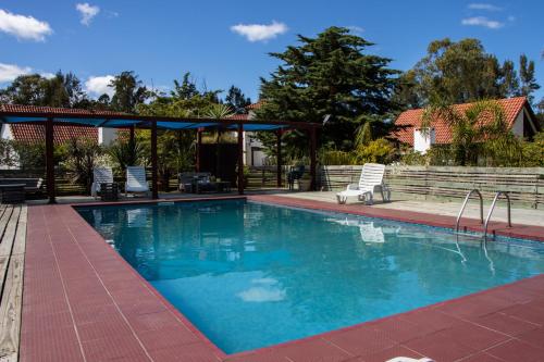 a swimming pool with chairs and a gazebo at Bellamar Apart Hotel in Bella Vista