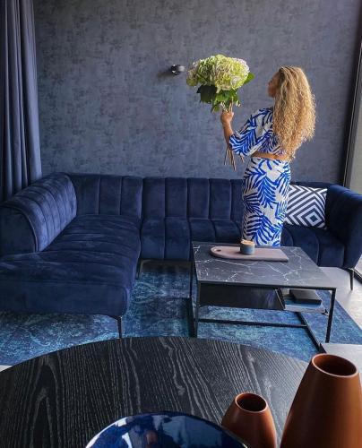a woman in a living room holding a vase of flowers at Exklusive Design Appartement Palm Paradise Neubau in Pfungstadt