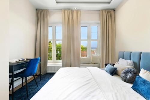 Un dormitorio con cama, escritorio y ventanas en Elite Apartments Ogarna Suites Old Town, en Gdansk