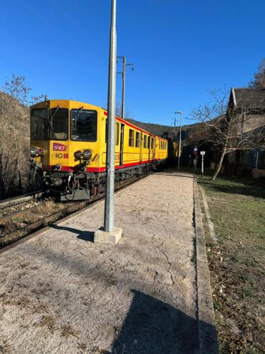 een gele trein zit op het spoor bij Charmant appartement in Serdinya