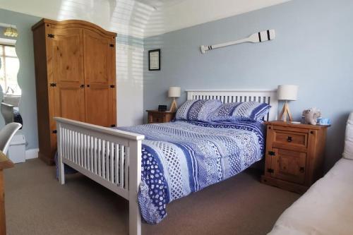 a bedroom with a bed with a blue and white comforter at Sunny Family Residence with parking. Jacuzzi bath perfect for relaxing and unwinding in Kent