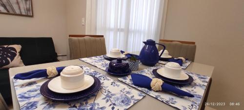a table with blue and white plates and hats on it at Paraíso Peracanga - Bacutia in Guarapari