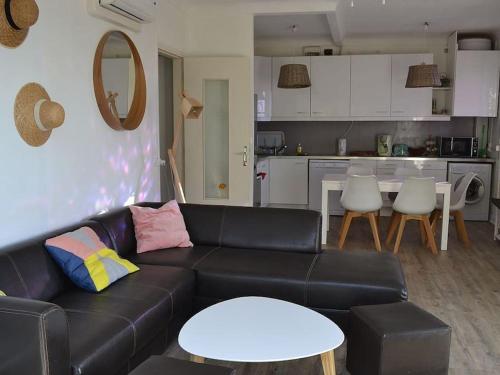 un salon avec un canapé noir et une cuisine dans l'établissement VILLA face à la plage avec terrasse et jardin, à Narbonne