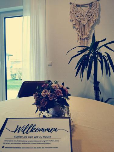 a sign sitting on a table with a bouquet of flowers at Ferienwohnung Martinsesch in Bad Schussenried