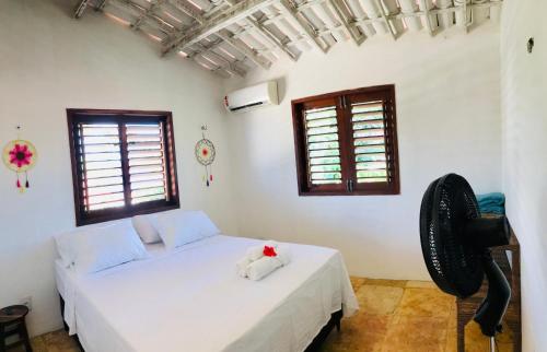 a bedroom with a bed and a fan at Pousada Tangerina in Icaraí