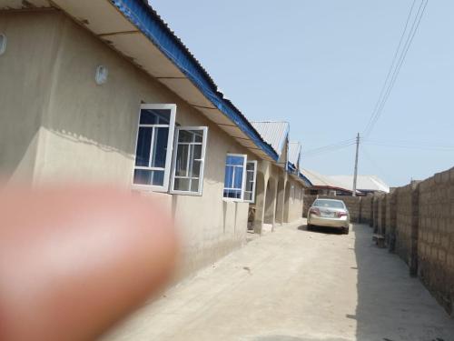 une voiture garée à côté d'un immeuble avec une clôture dans l'établissement Abakidoye Lodge, à Ilora