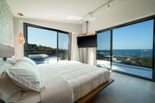 a bedroom with a large bed and large windows at Nivo Luxury Villa in Giannoudi