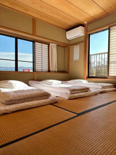 uma fila de três camas num quarto com janelas em 吉祥莊 em Takayama