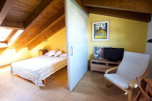 a bedroom with a bed and a chair and a television at Casa Pirineu in Alp