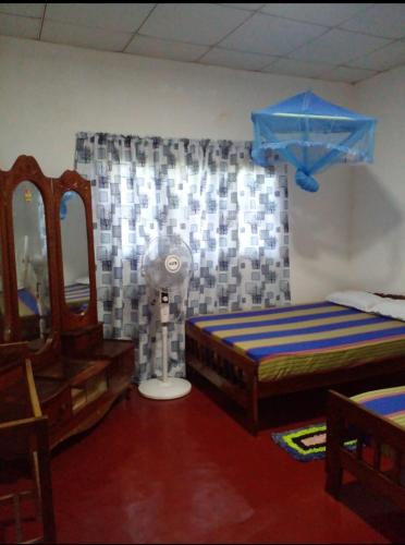 a bedroom with two beds and a mirror and a fan at Sanasuma Piyasa Holiday Home in Anuradhapura