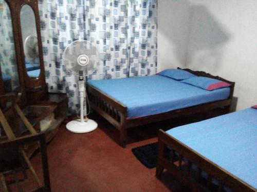 a bedroom with two beds and a fan and a mirror at Sanasuma Piyasa Holiday Home in Anuradhapura