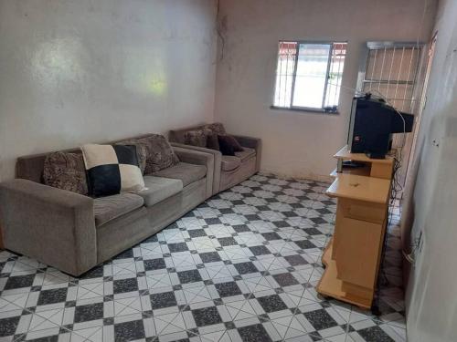 een woonkamer met een bank en een tv bij Casa em berlinque, vera cruz. in Vera Cruz de Itaparica