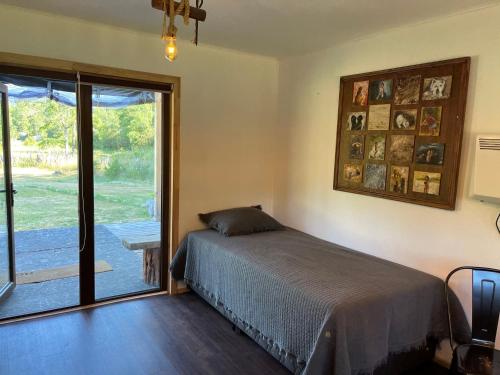 a bedroom with a bed and a sliding glass door at Linda Cabaña pet friendly a orilla rio y bosque, cerca Termas in Panguipulli