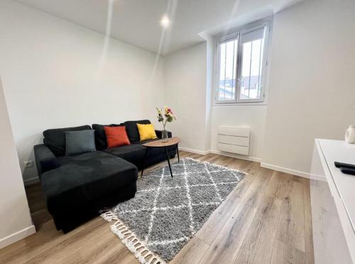 un salon avec un canapé noir et une table dans l'établissement L Eclat - Logement moderne proche Paris - Wifi, à Rueil-Malmaison