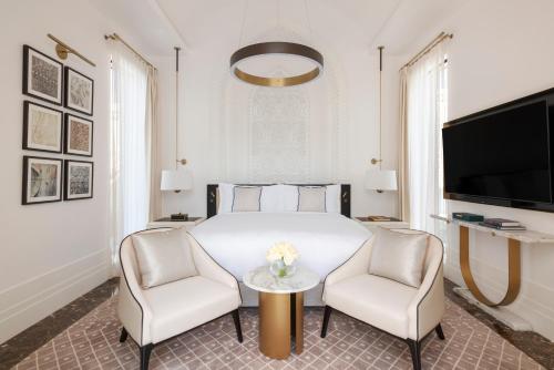 a bedroom with a bed and two chairs and a table at Raffles Al Areen Palace Bahrain in Manama