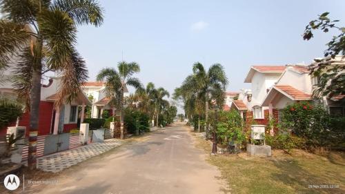 an empty street with houses and palm trees at Raj Kuthir Homestays - Sobuj Potro in Bolpur