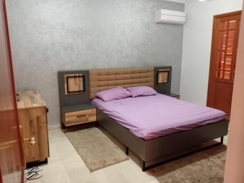 um quarto com uma cama com lençóis roxos e uma mesa de cabeceira em Marrakech em Marrakech