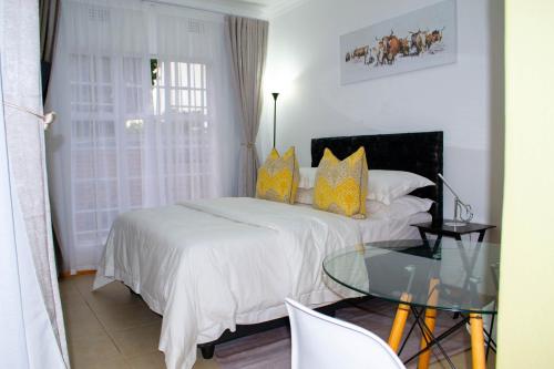 1 dormitorio con cama y mesa de cristal en Fafi's Place en Johannesburgo