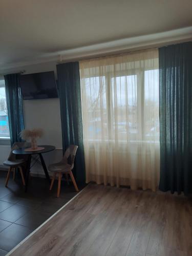 a living room with a table and chairs and a window at Studio Apartment in Rēzekne