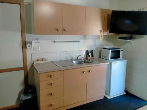a small kitchen with a sink and a microwave at Oakey Motel in Oakey