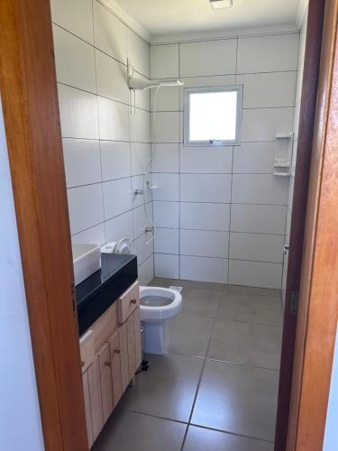 uma casa de banho com um WC, um lavatório e uma janela em Casa a 50 metros do mar em Itati