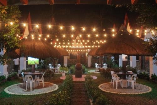 a patio with tables and chairs at night with lights at Bea's Garden Inn in Puerto Princesa City