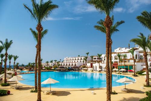 a pool with palm trees and buildings in the background at Savoy Sharm El Sheikh in Sharm El Sheikh