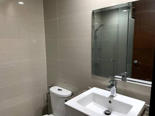 a bathroom with a sink and a toilet and a mirror at Escape 1BR One Uptown BGC w/ Sound System in Manila