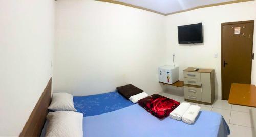 Schlafzimmer mit einem blauen Bett und einem TV in der Unterkunft Pousada 4 estações in Madre de Deus