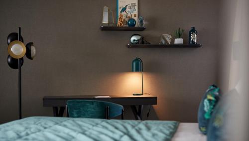 a bedroom with a desk with a lamp and a bed at Van der Valk Hotel Brussels Airport in Diegem