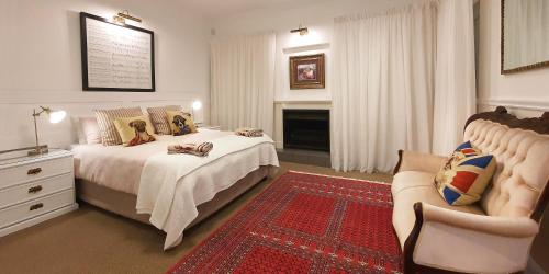 a bedroom with a bed and a chair and a fireplace at Die Kasteel, Belvidere Estate in Knysna
