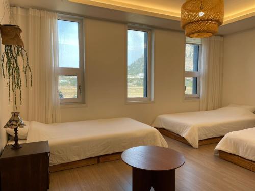 a bedroom with two beds and a table and windows at Misun House in Seogwipo
