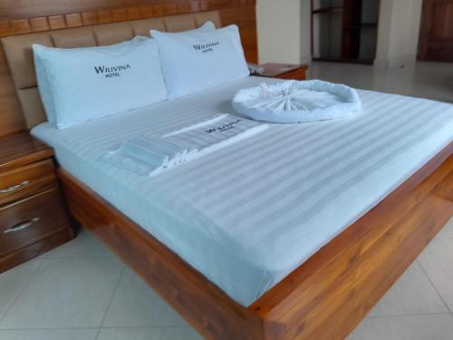 a bed with white sheets and pillows on it at WILIVINA HOTEL in Dar es Salaam