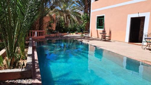 - une piscine d'eau bleue en face d'une maison dans l'établissement Au jardin de Tamnougalt, à Agdz