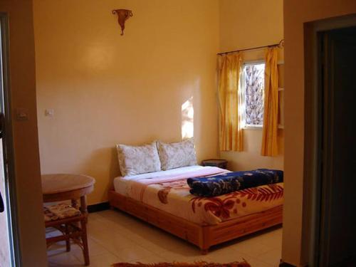 a bedroom with a bed and a window at Au jardin de Tamnougalt in Agdz