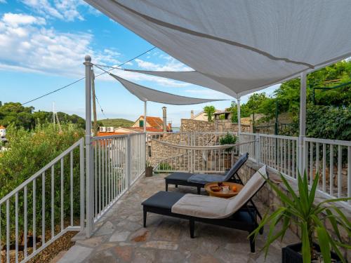a patio with a white umbrella and chairs on a balcony at Holiday Home Lea in Maslinica