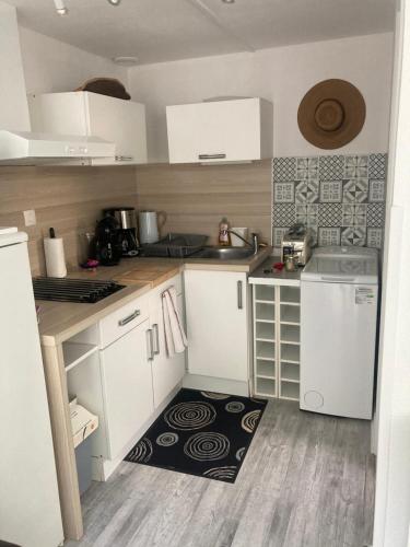 une petite cuisine avec des placards blancs et un tapis dans l'établissement Appartement duplex lumineux idéalement situé, à Arès