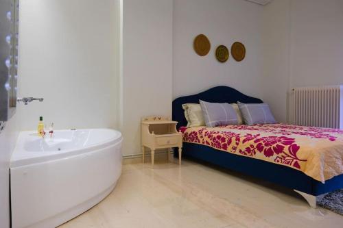 a bathroom with a tub next to a bed and a bath tub at NGsuite cityspot Volos in Volos