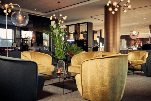 a lobby with chairs and a table and a bar at Van der Valk Hotel Brussels Airport in Diegem