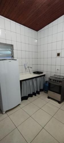 uma cozinha em azulejos brancos com um fogão e um frigorífico em Casinha Pescador em São Sebastião