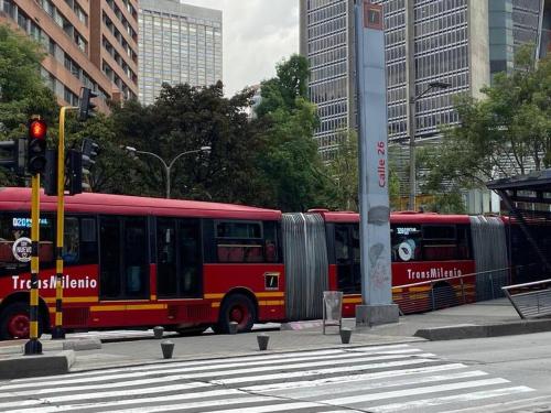 a red bus is driving down a city street at Apartaestudio Bogotá Colombia in Bogotá