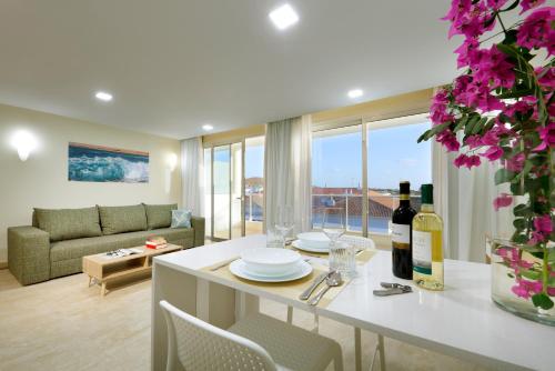 Marinell Collection Palm-Mar Apartments في بالم مار: مطبخ وغرفة معيشة مع طاولة مع زجاجة من النبيذ