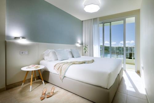 a bedroom with a white bed and a balcony at Marinell Collection Palm-Mar Apartments in Palm-mar