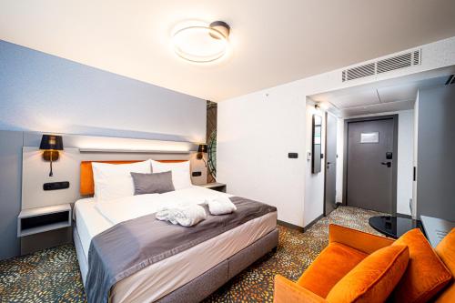 a hotel room with a large bed with orange pillows at Hotel Helikon, Keszthely in Keszthely