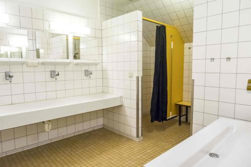 a white tiled bathroom with a sink and a mirror at Jugendherberge Husum in Husum