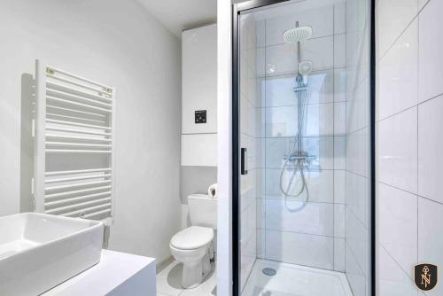 uma casa de banho branca com um chuveiro e um WC. em La Casa Naia V — Votre bulle d'air sur la côte em Douvres-la-Délivrande